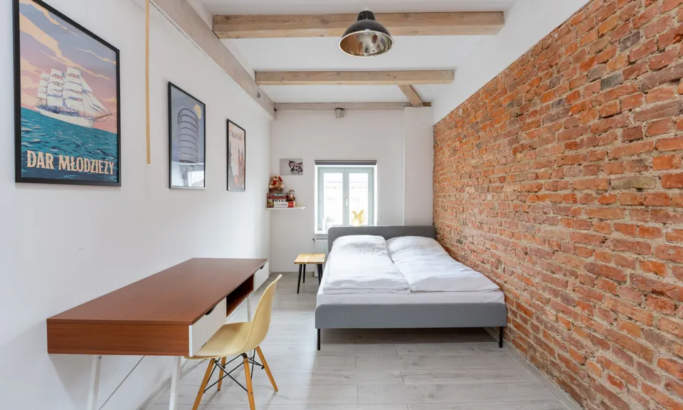 Sypialnia z ceglaną ścianą w apartamencie przy ul. Ratajczaka 25