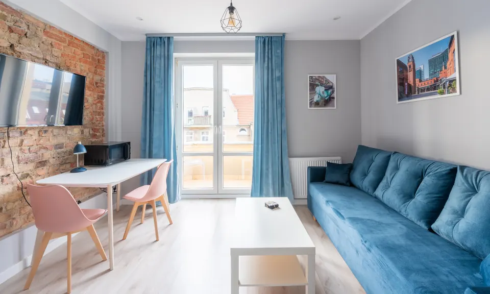 Studio z ceglaną ścianą, sofą i drzwiami na balkon