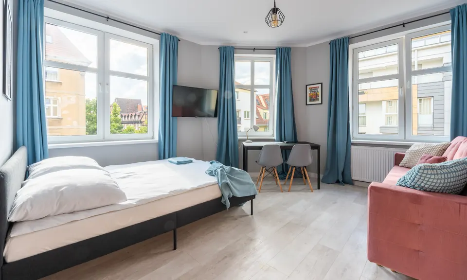 Łóżko pod oknami i sofa