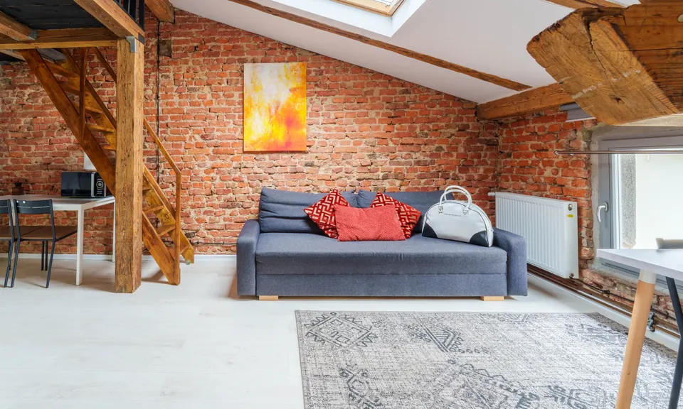 Sofa pod ceglaną ścianą i oknem dachowym