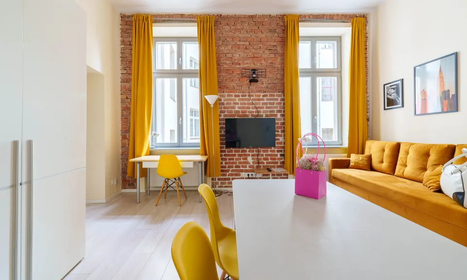 Sofa pod ceglaną ścianą i dwa okna